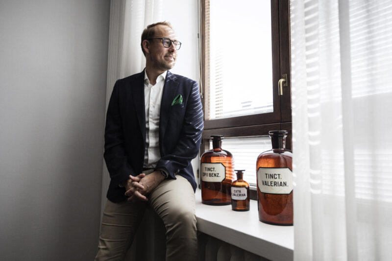 Juha-Pekka Ojala kuvattuna istumassa puolittain toimistonsa ikkunalaudalla.