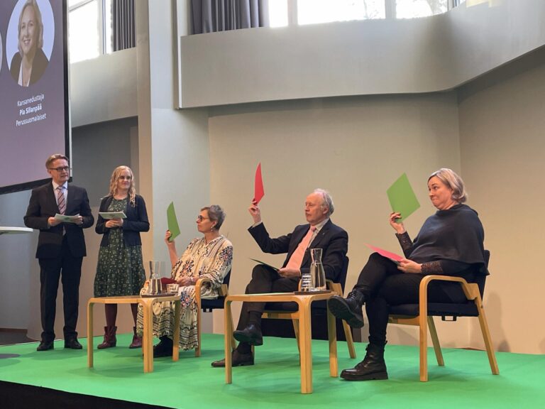 Panelistit äänestävät näyttämällä punaisia ja vihreitä lappuja.