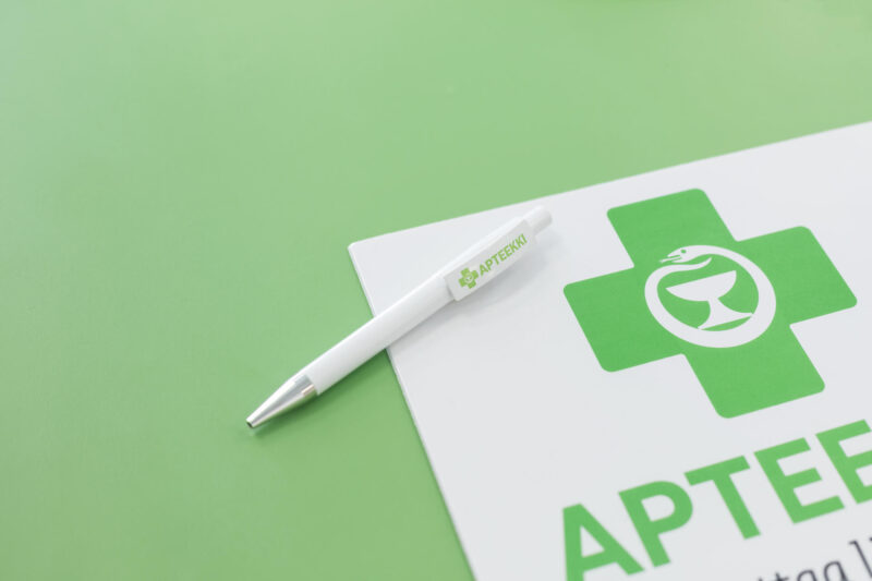 Apteekkariliiton vihreän ristin logo ja kynä.