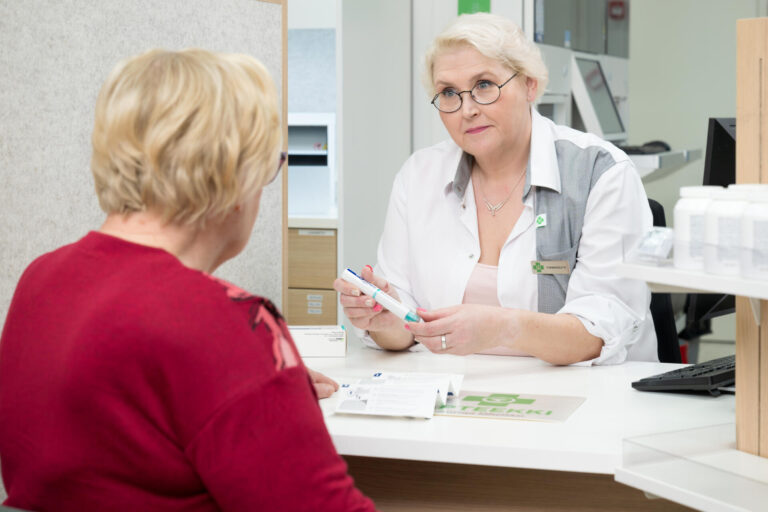 Apteekin farmaseutti esittelee asiakkaalle biologisen lääkkeen antolaitetta.