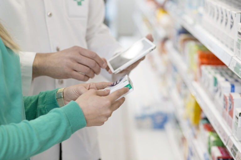 Asiakas ja farmaseutti itsehoitolääkehyllyn edessä.