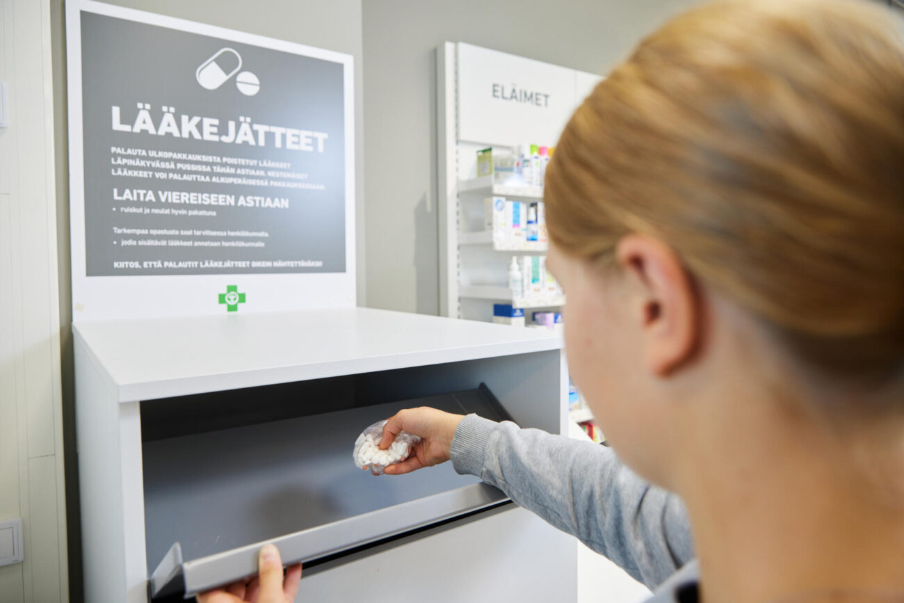 Nuori nainen palauttamassa käyttämättä jääneitä lääkkeitä apteekin lääkejäte-astiaan.