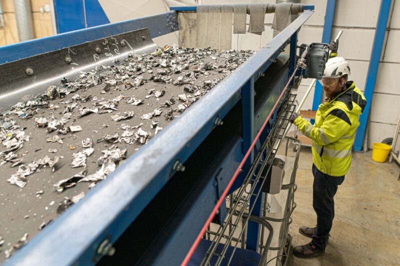 Kuusankosken työntekijät käsittelemässä jätettä, joka on murskeena hihnalla.