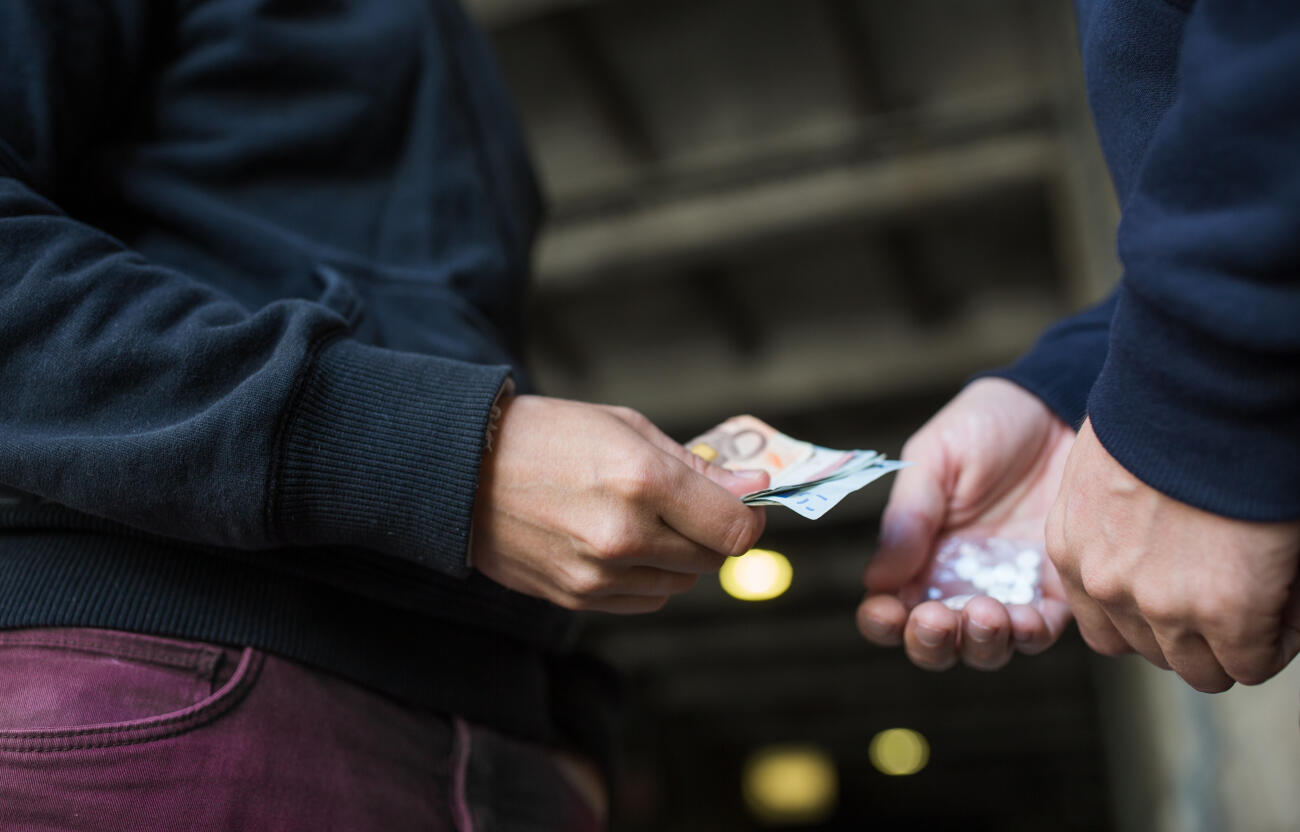 drug trafficking, crime, addiction and sale concept - close up of addict with money buying dose from dealer on street INGIMAGE